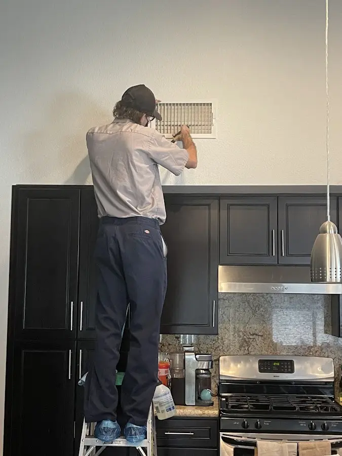 Technician inspecting an air vent during HVAC service in Loveland